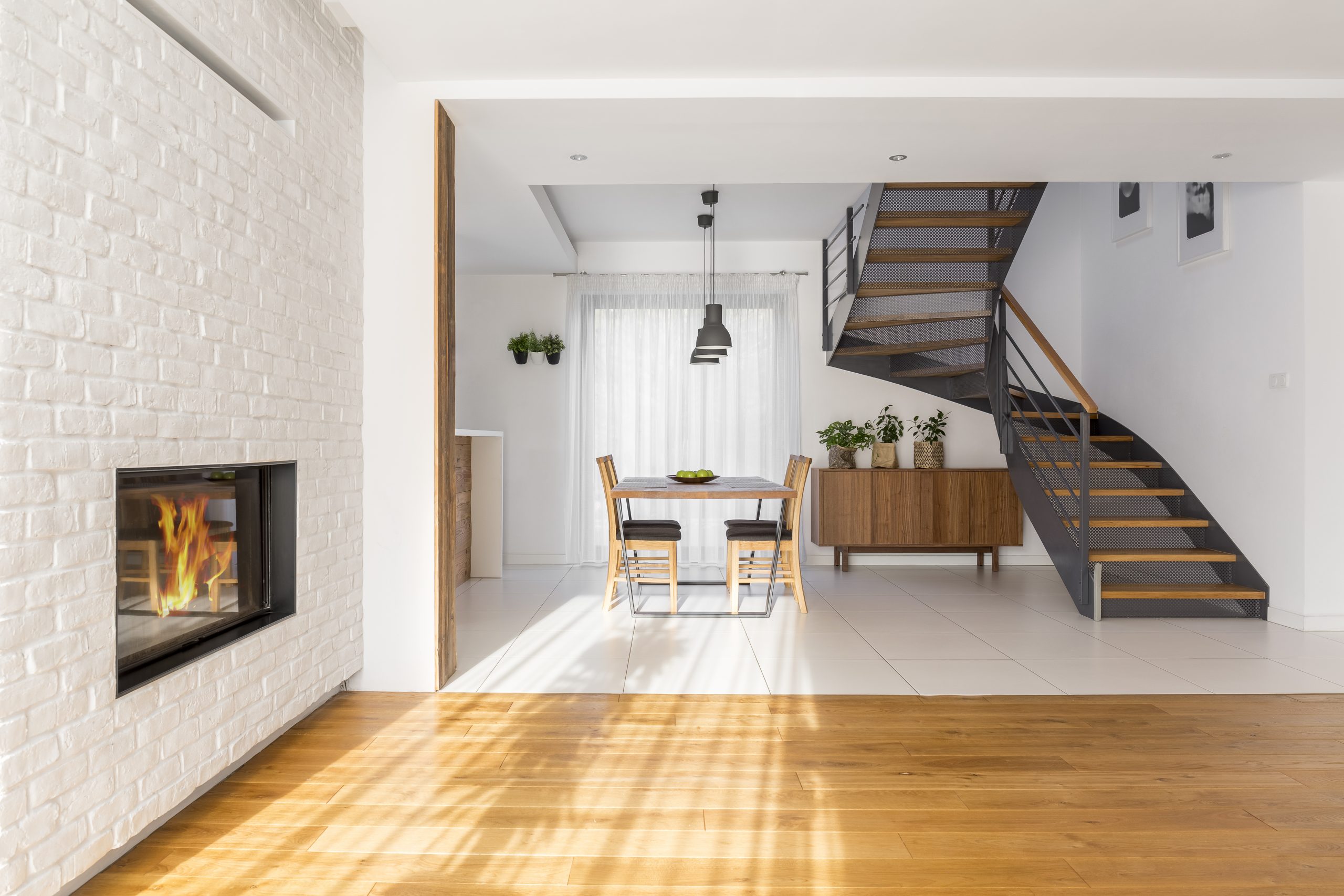 Modern, white apartment with fireplace, table and staircase